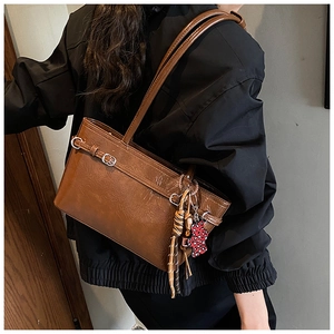 Detail of vintage brown shoulder bag with leopard print charm and tassel pendant