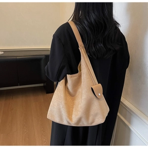 Close-up of camel suede hobo tote bag with wide strap and matching mini pouch on a model