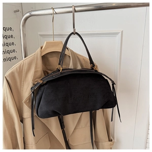 Detail of black suede leather handbag with embossed brand logo and adjustable shoulder strap