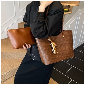 Détail d'un sac cabas marron avec texture grain de bois, gland perlé et pochette assortie