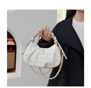 Detail view of plaid crescent bag with ruffled handle and adjustable crossbody strap