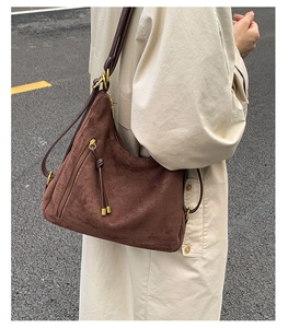 Detail of dark brown suede hobo bag with fringe zipper and knots on a trench coat