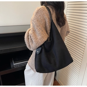 Detail of minimalist black suede hobo bag with metal snap button and matte finish texture