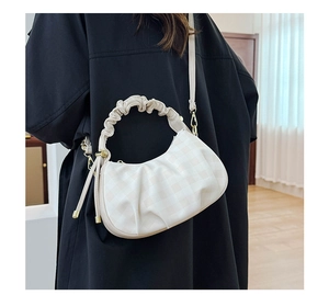 Detail of light beige plaid dumpling bag featuring pleated handle and gold hardware