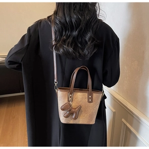Rear view of a model wearing a brown vintage bucket bag with a cute puppy pendant