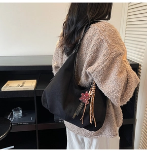 Détail du sac hobo en daim noir avec pendentif cœur léopard rouge et glands tressés