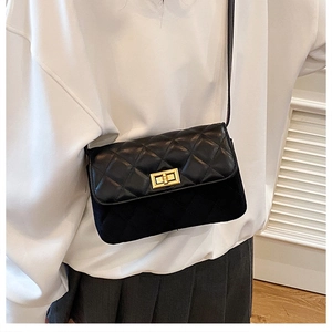 Detail of classic black quilted pattern with gold rectangular twist lock on shoulder bag