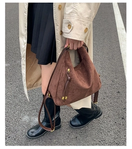 Detail of vintage matte brown backpack with tassel zipper and metal hardware in outdoor setting