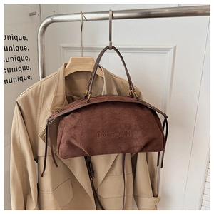 Detail of a brown suede Boston bag featuring embossed logo and retro bronze hardware