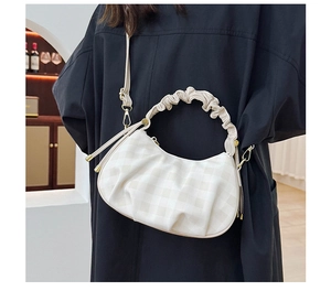 Detail of beige checkered dumpling bag with cloud pleats and gold-tone hardware on black coat