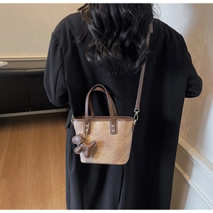Brown vintage bucket bag worn as a crossbody by model in minimalist interior style