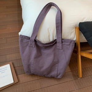 Close-up of a large purple canvas tote bag placed on a minimalist wooden floor