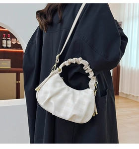 Model wearing white checkered dumpling bag with cloud pleated handle and gold hardware