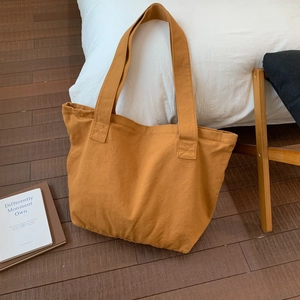 Detailed view of reinforced stitching on mustard yellow canvas tote bag handle and texture