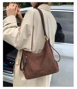 Detail of dark brown matte suede tote bag with metal zipper and adjustable strap