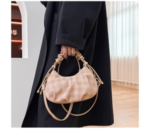 Detail of beige plaid dumpling bag with pleated handle and adjustable crossbody strap