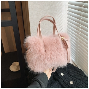 Close-up of fluffy pink faux fur handbag with leather handles and gold metal buckles