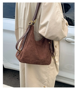 Detail of dark brown matte suede hobo bag with adjustable leather strap and gold buckle
