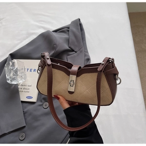 Close-up of quilted suede shoulder bag with retro metal lock on grey blazer background