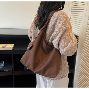 Macro view of dark brown suede hobo bag detailing soft texture and decorative side buckle