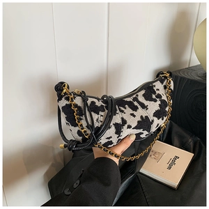 Dettaglio borsa a mezzaluna con stampa mucca in jacquard e catena dorata elegante
