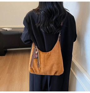 Sac hobo en daim marron avec détails de franges, porté par un mannequin en intérieur