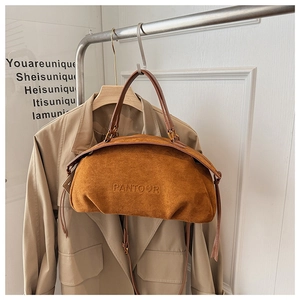 Detail of dark brown suede handbag with embossed logo hanging on a metal rack