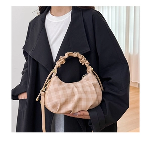 Detail of checkered beige pleat dumpling bag with scrunchie handle and gold buckle