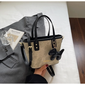 Detail of olive green suede bucket bag with gold logo and black dog charm detail