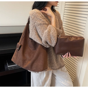 Brown suede hobo bag and matching zipper pouch set shown in a minimalist indoor setting