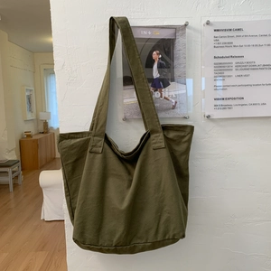 Minimalist olive green canvas tote bag for women with large capacity on white textured wall
