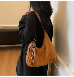 Détail du sac hobo en daim caramel avec franges décoratives et pendentif ours sur le modèle