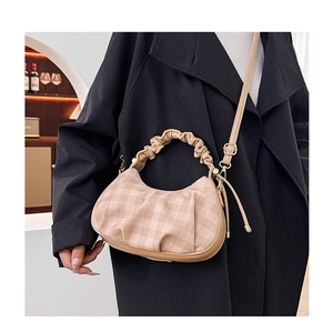 Beige plaid cloud bag with pleated handle and strap shown on a trench coat outfit