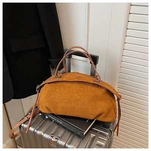 Close-up of brown suede oversized handbag with embossed logo on metal luggage