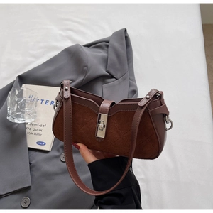 Detail of dark brown quilted suede handbag featuring a silver rectangular twist lock closure