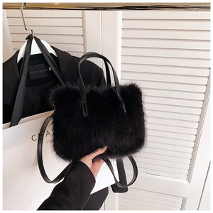 Close-up of a fluffy black faux fur handbag with a leather handle and shoulder strap