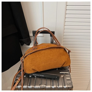Detail of vintage camel suede Boston bag with embossed logo and tassel on a suitcase