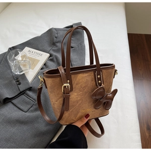 Detailed view of a brown vintage bucket bag with a dog charm on a blazer background