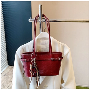 Detail view of retro burgundy leather tote bag with pleats and heart tassel charm