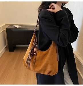 Détail du sac hobo en daim marron avec franges et pendentif cœur sur la bandoulière