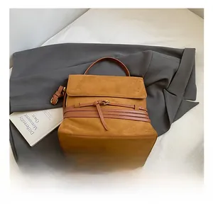 Detalle de la mochila de ante marrón caramelo con correas de hebilla y asa superior