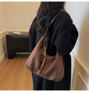 Gros plan du sac hobo en daim marron avec pendentif ours léopard et franges