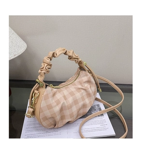 Detail of checkered dumpling bag featuring pleated stretch handle and gold metal hardware