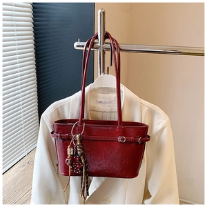 Detail of burgundy textured leather handbag with fringe and star charm hanging on its side