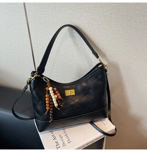 Close-up of black quilted shoulder bag with beaded fringe tassel and gold twist lock