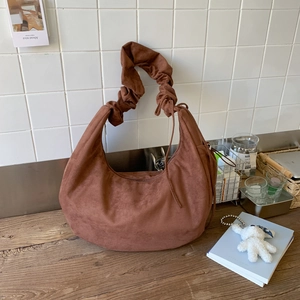 Detail of dark brown faux suede hobo bag with ruffled handle and drawstring texture