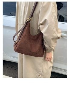 Close-up of a deep brown suede hobo bag with adjustable leather strap and gold hardware