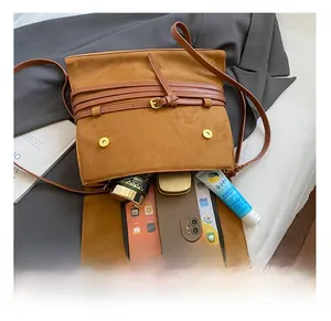 Interior espacioso del bolso de gamuza marrón con tableta y artículos cotidianos