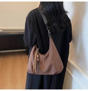 Sac hobo en daim marron avec pendentif à franges ethniques porté par un mannequin