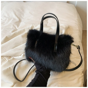 Close-up of soft black plush handbag with fluffy faux fur texture and leather strap